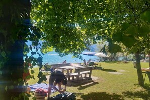 Ein Picknickplatz mit Tisch und Bänken, einer Rasenfläche und Blick auf das Wasser.