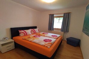 A bedroom with a bed, a nightstand, a window with curtains, and a wall-mounted artwork. - Holiday home with 1 bedroom (Unterach am Attersee)