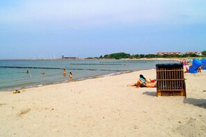 A beach with people swimming and sunbathing, a lifeguard tower, and beach umbrellas. - Holiday home with 3 bedrooms (Glowe\/Rügen)