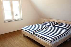 A single bed with a striped bedspread in a room with a sloped ceiling and a window. - Holiday home with 3 bedrooms (Glowe\/Rügen)