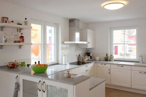 A modern kitchen with white cabinets, a granite countertop, and a built-in oven. - Holiday home with 3 bedrooms (Glowe\/Rügen)