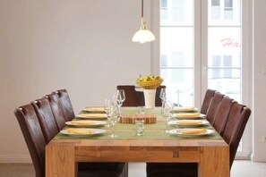 A dining table set for six with a green placemat, surrounded by six brown leather chairs, and a hanging light fixture above. - Holiday home with 3 bedrooms (Glowe\/Rügen)