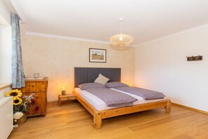 Ein Schlafzimmer mit einem hölzernen Bett, einem Nachttisch, einer Kommode und einer Pendelleuchte.