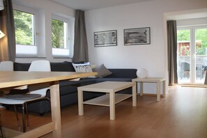 A modern living room with a sofa, two coffee tables, and a dining table. - Holiday apartment in Waren with swimming pool (Waren)