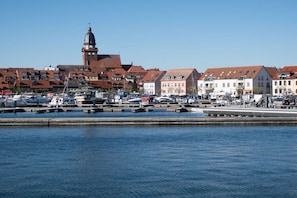 A marina with boats docked, a prominent building with a dome, and a row of residential buildings with red roofs. - Holiday apartment in Waren with swimming pool (Waren)