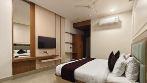 Een moderne hotelkamer met een bed, een flatscreen televisie, een plafondventilator en inbouwopbergruimte.