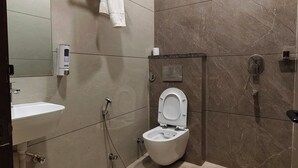 A modern bathroom with a toilet, sink, and shower. - Hotel Royal DC (Aligarh)