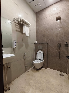 A modern bathroom with a toilet, sink, and shower. - Hotel Royal DC (Aligarh)