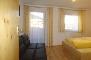 A room with a bed, a sofa, and a window with curtains.