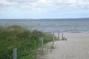 A sandy beach with a grassy area and a wooden fence. - Holiday home in Glowe with swimming pool (Glowe)