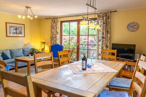 A dining area with a wooden table, chairs, and a television. - Holiday home in Glowe with swimming pool (Glowe)