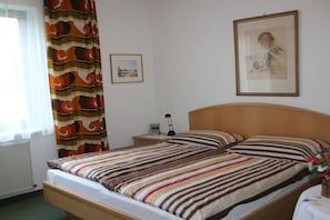 Ein Hotelzimmer mit einem Einzelbett, einem Nachttisch, einer Lampe und einem gerahmten Bild an der Wand.