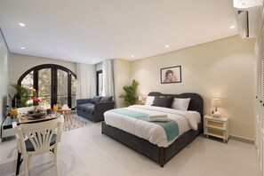 A modern bedroom with a large bed, a desk with a chair, and a dining area. - Amazing Deal at Bait Assel by Spacey #91 (cairo)