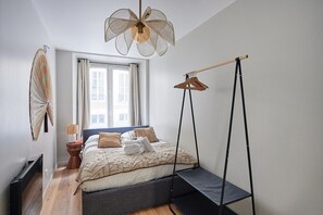 Ein Schlafzimmer mit Bett, Deckenventilator, Fenster und Heizkörper.