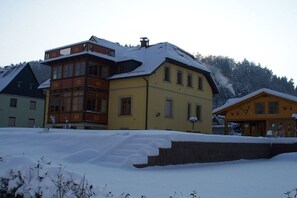Un edificio a più piani con un tetto imbiancato dalla neve e un camino che emette fumo.