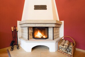 Ein Kamin mit Feuer, einem Sims und einem Holzkorb.