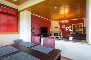 Zona pranzo con tavolo e sedie in legno, televisione e camino.
