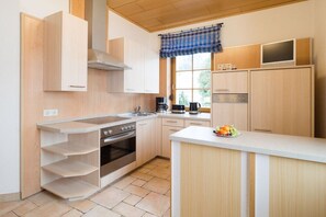 Eine moderne Küche mit Holzschränken, einem Edelstahlherd und einem eingebauten Backofen.