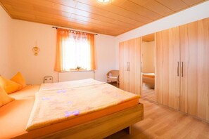 A bedroom with a bed, a wardrobe, and a window with curtains. - Holiday apartment with 2 bedrooms (Bad Schandau)