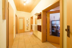 Ein Hotelgang mit einer Holztür, einem Spiegel und einem Fenster.