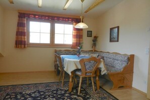 Un coin repas avec une table dressée pour quatre personnes, un banc et un tapis à motifs.