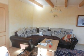 A living room with a dark brown sofa, patterned cushions, a wooden coffee table, and a hanging light fixture. - Holiday apartment with 1 bedroom (Mariapfarr)