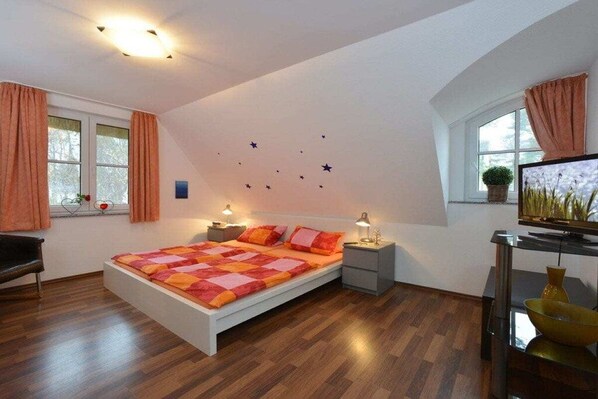 A bedroom with a bed, bedside tables, a TV, and a window with curtains. - Holiday home in Glowe with swimming pool (Glowe)