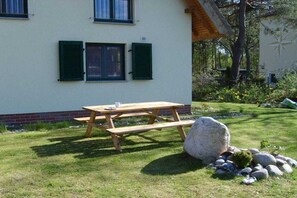 A wooden picnic table with benches in front of a building with green shutters. - Holiday home in Glowe with swimming pool (Glowe)