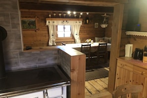 Un interior de madera con área de cocina, mesa de comedor y sillas.