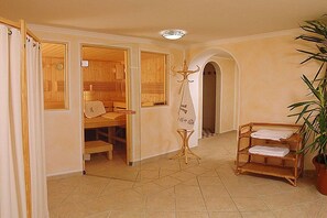 Une salle de spa équipée d’un sauna en bois, d’un porte-serviettes et d’une plante en pot.