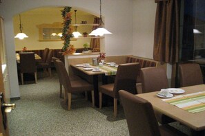 A dining area with tables and chairs, a chandelier, and a view of the dining room in the background. - Holiday apartment with 2 bedrooms (Neustift)