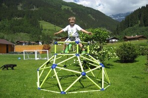 A child playing on a geodesic dome structure in a grassy field with houses and mountains in the background. - Holiday apartment with 2 bedrooms (Neustift)