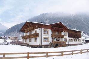 A traditional wooden chalet with balconies, set against a snowy mountain backdrop. - Holiday apartment with 2 bedrooms (Neustift)