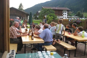 A group of people seated at wooden tables outdoors, with a mountainous backdrop. - Holiday apartment with 2 bedrooms (Neustift)
