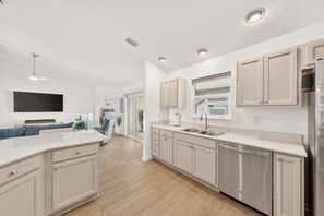 A modern kitchen with a central island, built-in cabinets, and a stainless steel refrigerator. - Fowl Play - 3/2 w/ 4-Seat Golf Cart in The Villages - Oak Hallow (The Villages)