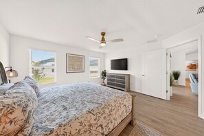 A bedroom with a bed, a ceiling fan, a dresser, a TV, and a door leading to another room. - Fowl Play - 3/2 w/ 4-Seat Golf Cart in The Villages - Oak Hallow (The Villages)