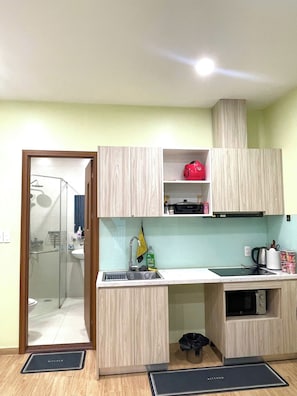 Uma cozinha compacta com pia, micro-ondas e armários de madeira.