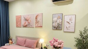 Quarto com cama, mesa de cabeceira, luminária, cadeira e planta em vaso.
