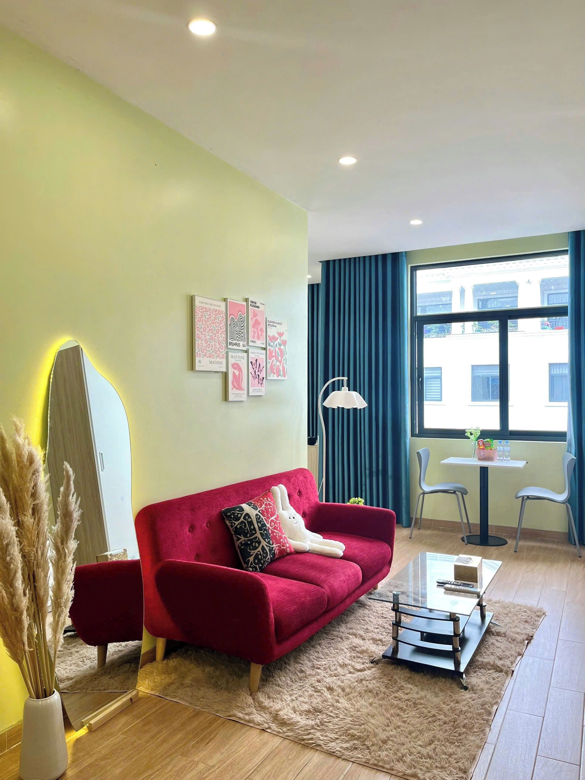 Una sala moderna con un sofá rojo, una mesita y un espejo.