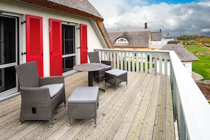 Eine Holzterrasse mit Korbmöbeln und einem weißen Geländer.