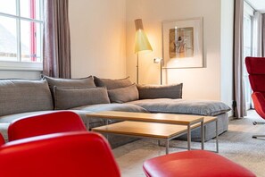 A modern living room with a sectional sofa, a wooden coffee table, and red chairs. - Holiday home with 4 bedrooms (18445 Kramerhof, Deutschland)