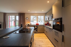 A modern kitchen with a central island, built-in appliances, and a view of the outdoors. - Holiday home with 4 bedrooms (18445 Kramerhof, Deutschland)