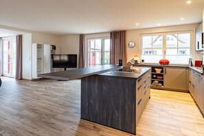 A modern kitchen with a central island, built-in cabinets, and a large window. - Holiday home with 4 bedrooms (18445 Kramerhof, Deutschland)