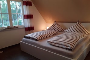Ein Bett mit gestreifter Bettwäsche in einem Zimmer mit Fenster und Vorhängen.