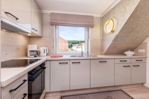 Een moderne keuken met een inbouwoven, koffiezetapparaat en een raam met uitzicht op gebouwen.