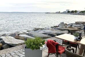 A seaside restaurant with outdoor seating, a view of the sea, and a rocky shoreline. - Holiday apartment with 1 bedroom (Saßnitz)