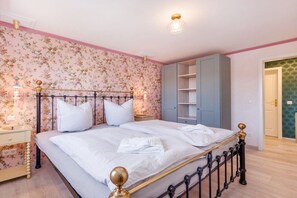 A bedroom with a bed, nightstands, a wardrobe, and a door leading to another room. - Holiday apartment with 1 bedroom (Saßnitz)