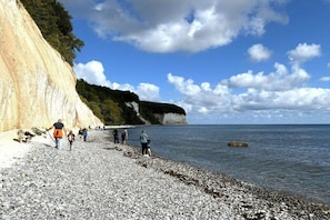 A pebbled beach with people walking, a cliff, and a clear sky. - Holiday apartment with 1 bedroom (Saßnitz)