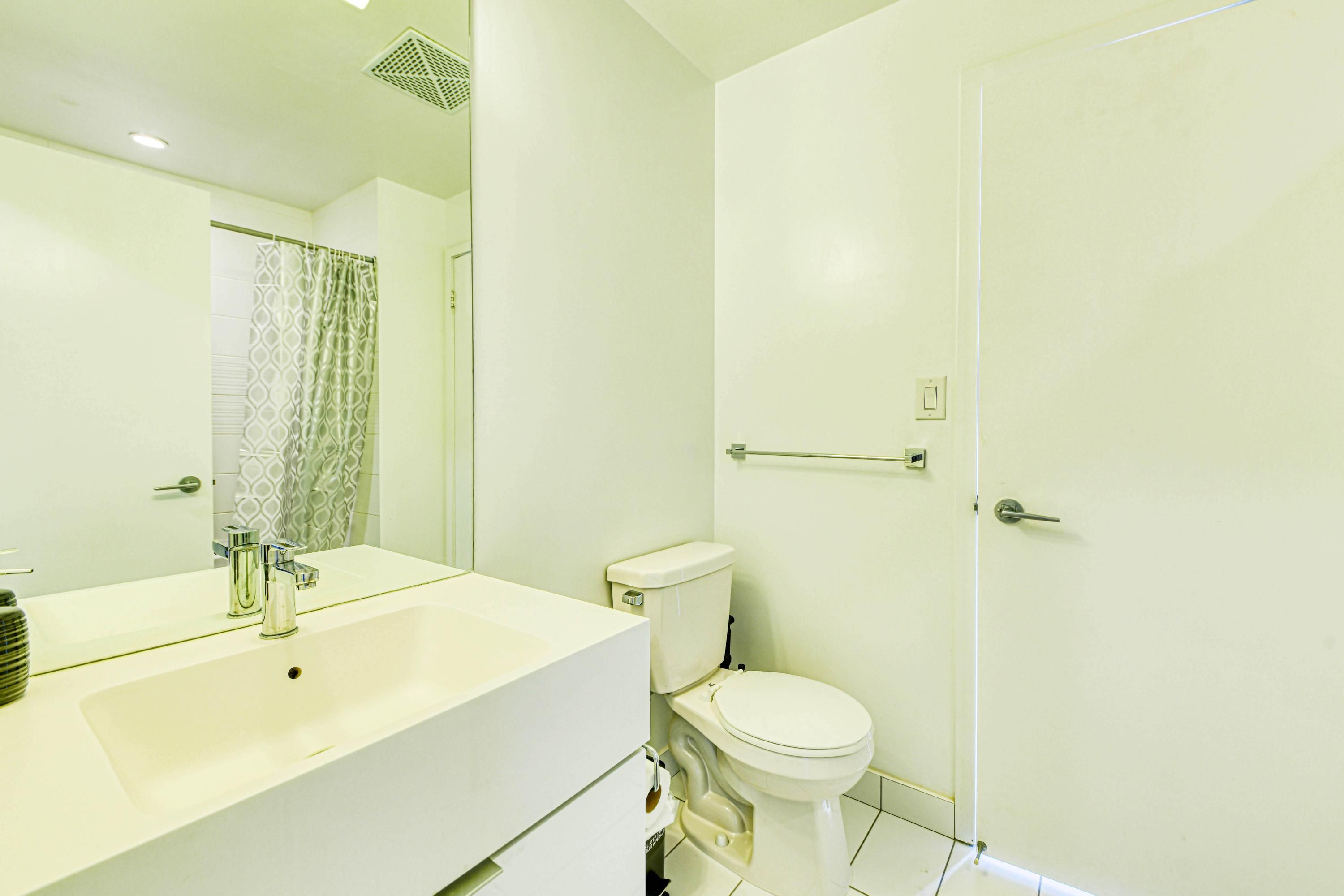 A modern bathroom with a white sink, a toilet, and a shower area.