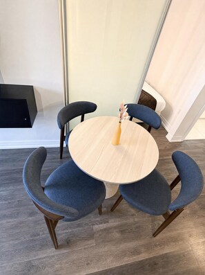 Un comedor con una mesa redonda de madera rodeada por cuatro sillas azules con patas de madera.